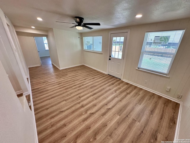 interior space featuring light wood-type flooring, a textured ceiling, and ceiling fan