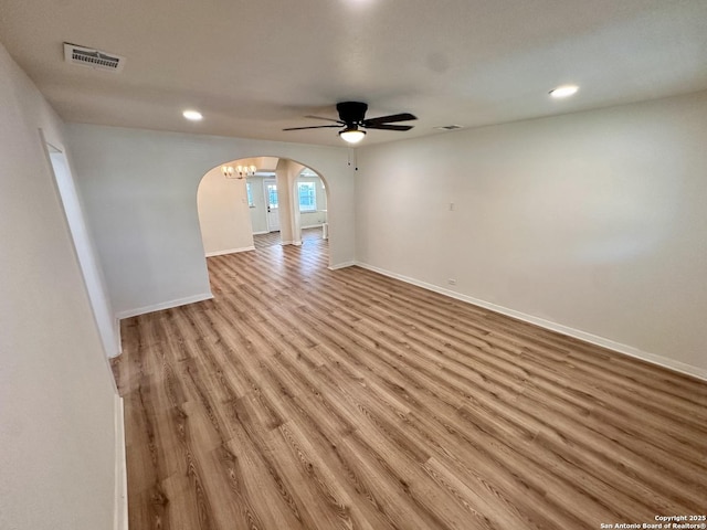 unfurnished room with light hardwood / wood-style flooring and ceiling fan with notable chandelier