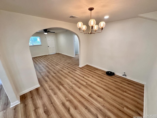 unfurnished dining area featuring ceiling fan with notable chandelier and wood-type flooring