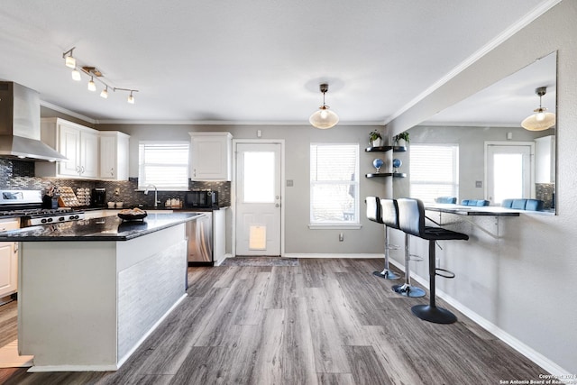 kitchen with white cabinetry, wall chimney range hood, hanging light fixtures, and range