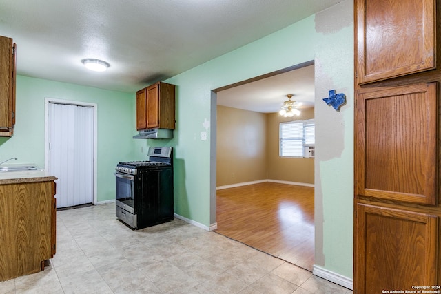 kitchen featuring sink, light hardwood / wood-style flooring, ceiling fan, a textured ceiling, and black range with gas cooktop