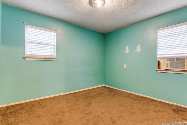 unfurnished room featuring carpet floors, cooling unit, and a textured ceiling