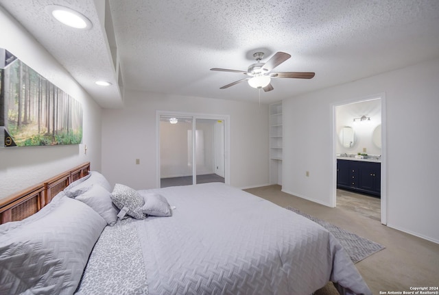 carpeted bedroom with a textured ceiling, ensuite bathroom, and ceiling fan