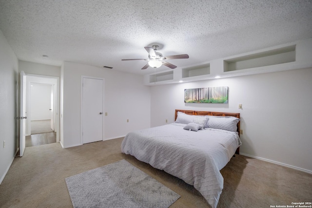 bedroom with ceiling fan, light colored carpet, and a textured ceiling