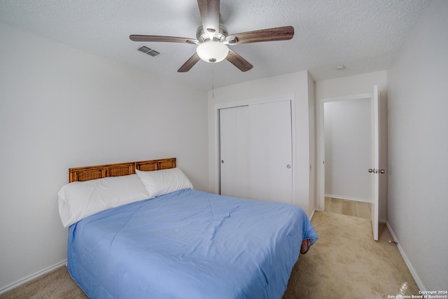 carpeted bedroom with a textured ceiling, a closet, and ceiling fan