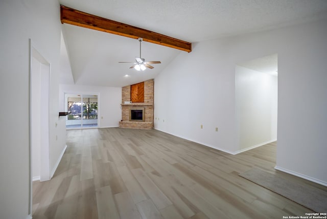 unfurnished living room with ceiling fan, lofted ceiling with beams, a fireplace, and light hardwood / wood-style flooring