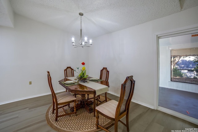 dining space with dark wood-type flooring, a textured ceiling, and a notable chandelier