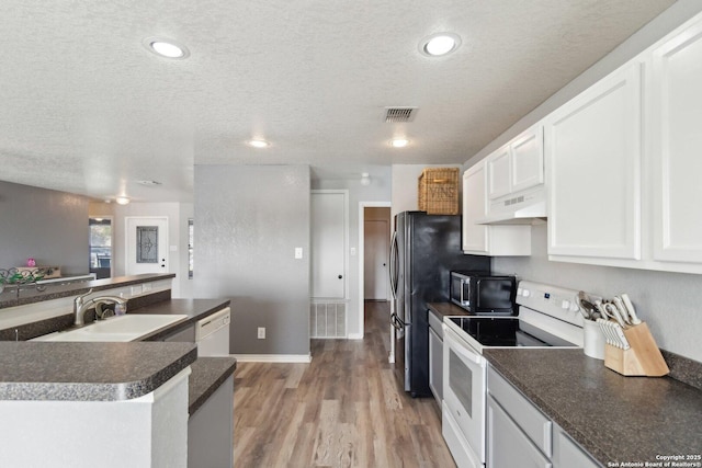 kitchen with a textured ceiling, sink, white cabinets, and white appliances