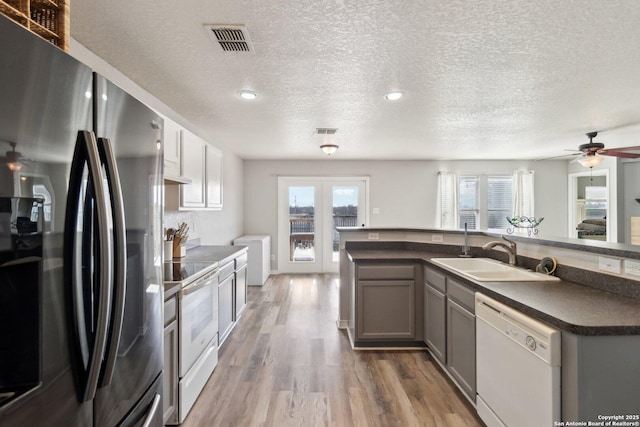 kitchen featuring white appliances, a textured ceiling, sink, wood-type flooring, and gray cabinets