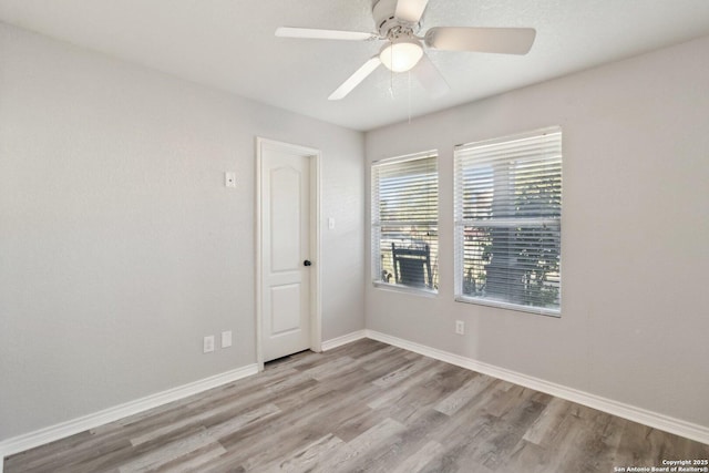 empty room with ceiling fan and light hardwood / wood-style flooring