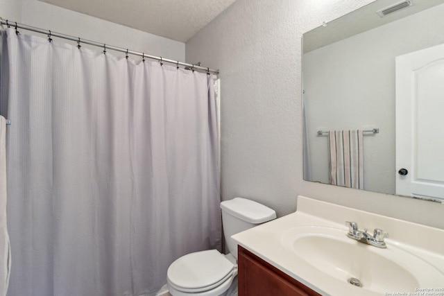 bathroom featuring vanity, a textured ceiling, and toilet