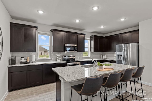 kitchen with a center island with sink, light hardwood / wood-style flooring, stainless steel appliances, and sink