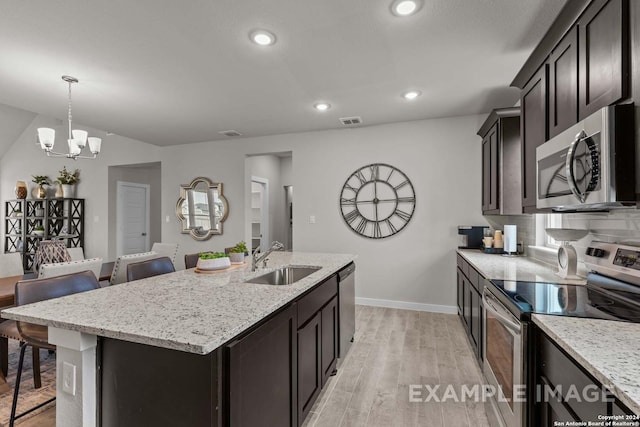 kitchen featuring stainless steel appliances, sink, a center island with sink, an inviting chandelier, and a breakfast bar area