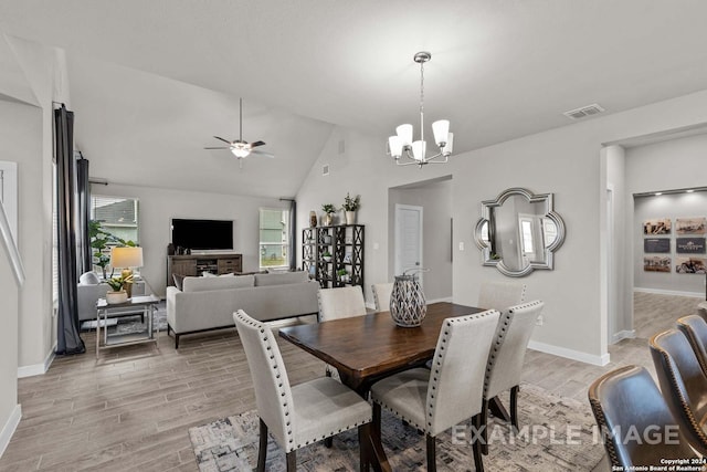 dining space with ceiling fan with notable chandelier, light wood-type flooring, and lofted ceiling