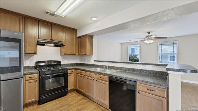 kitchen featuring black appliances, sink, light hardwood / wood-style flooring, ceiling fan, and kitchen peninsula