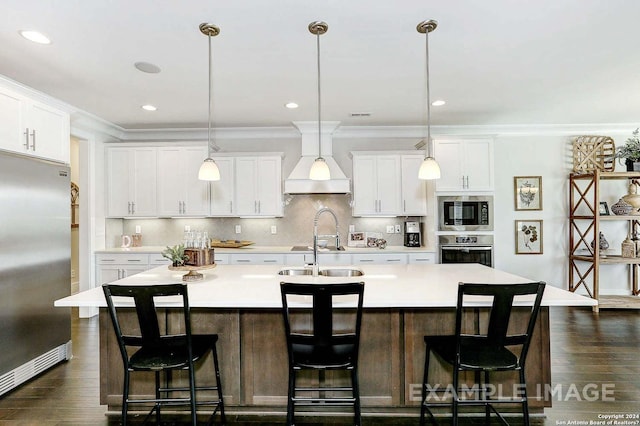 kitchen with a center island with sink, white cabinets, hanging light fixtures, and appliances with stainless steel finishes