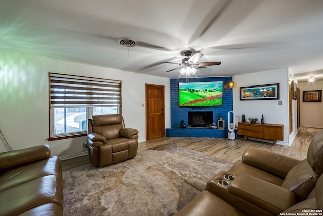 living room with ceiling fan, wood-type flooring, and a fireplace