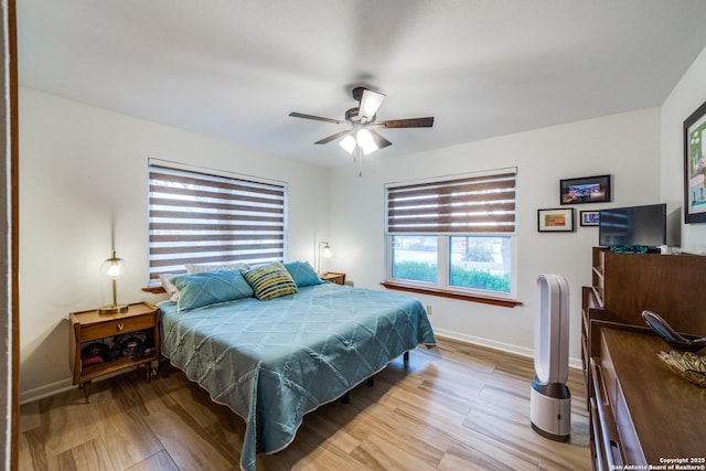 bedroom featuring ceiling fan, light hardwood / wood-style floors, and multiple windows