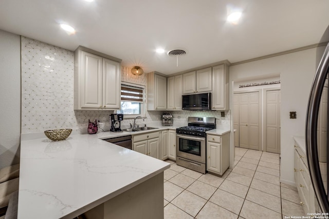 kitchen featuring sink, tasteful backsplash, light stone counters, light tile patterned floors, and appliances with stainless steel finishes