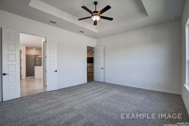 unfurnished bedroom with carpet, ceiling fan, and a tray ceiling