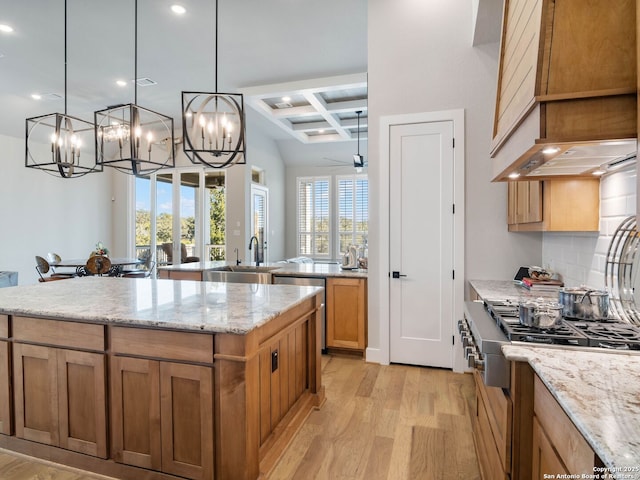 kitchen featuring decorative light fixtures, ceiling fan with notable chandelier, range, coffered ceiling, and a kitchen island