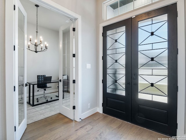 foyer with french doors, an inviting chandelier, and wood-type flooring