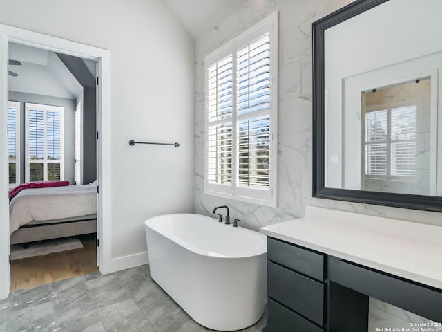 bathroom with lofted ceiling, a tub, tile walls, and vanity