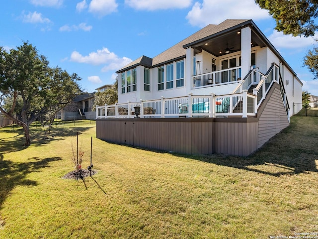 rear view of property featuring a yard, ceiling fan, and a balcony