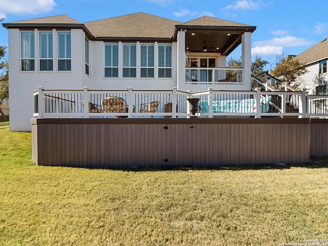 rear view of property featuring a lawn, ceiling fan, and a wooden deck