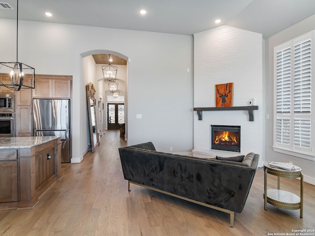 living room featuring a large fireplace, light hardwood / wood-style floors, and an inviting chandelier