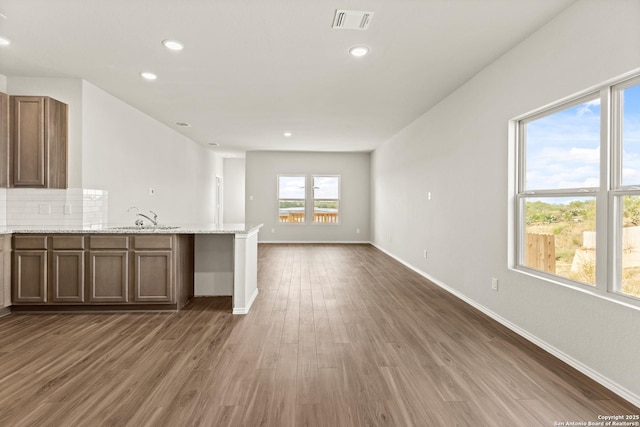 kitchen featuring light stone countertops, dark hardwood / wood-style flooring, backsplash, and sink