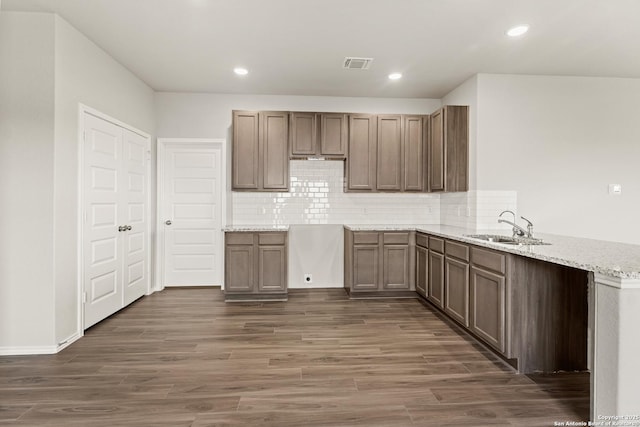 kitchen featuring kitchen peninsula, dark hardwood / wood-style flooring, light stone countertops, and sink