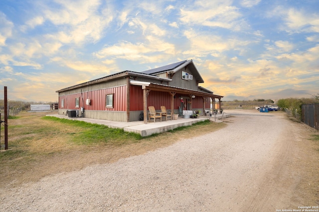 property exterior at dusk with solar panels, central AC, and a patio area