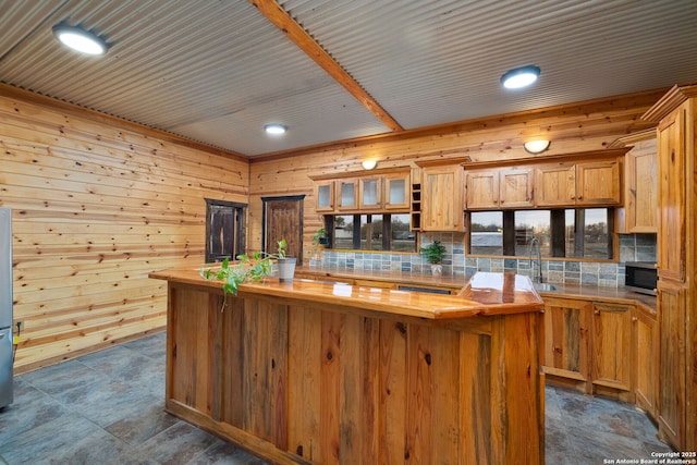 kitchen featuring a kitchen island, sink, wooden walls, and wooden counters