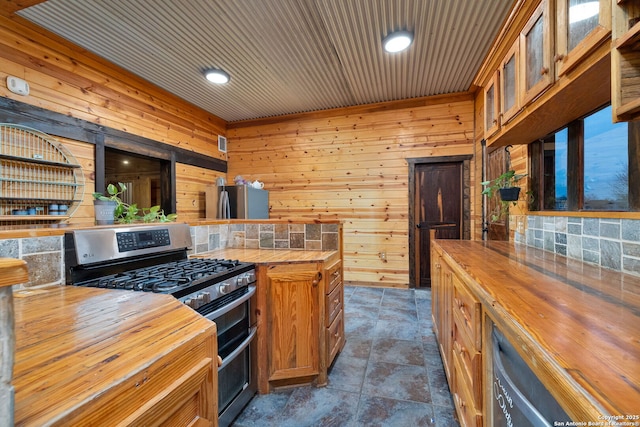 kitchen featuring appliances with stainless steel finishes, wooden walls, and butcher block counters