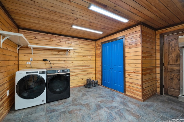 washroom with wood ceiling, wooden walls, and washing machine and clothes dryer