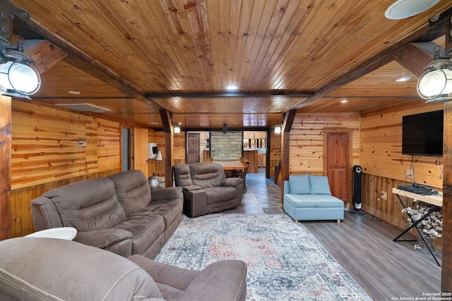 living room featuring ceiling fan, beamed ceiling, wooden ceiling, and wood walls