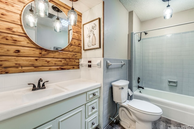 full bathroom with vanity, a textured ceiling, tile walls, toilet, and tiled shower / bath