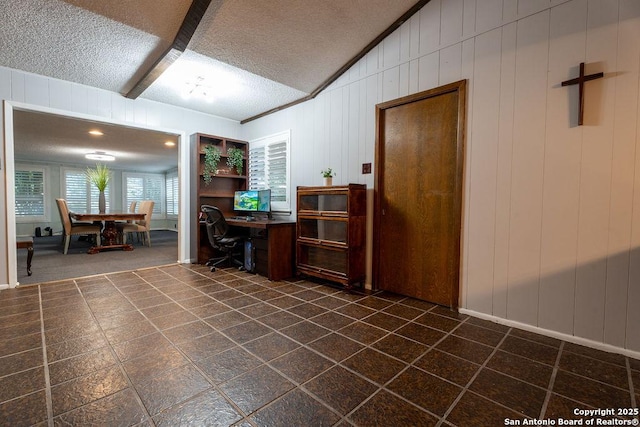 office area featuring beamed ceiling, a textured ceiling, crown molding, and wooden walls