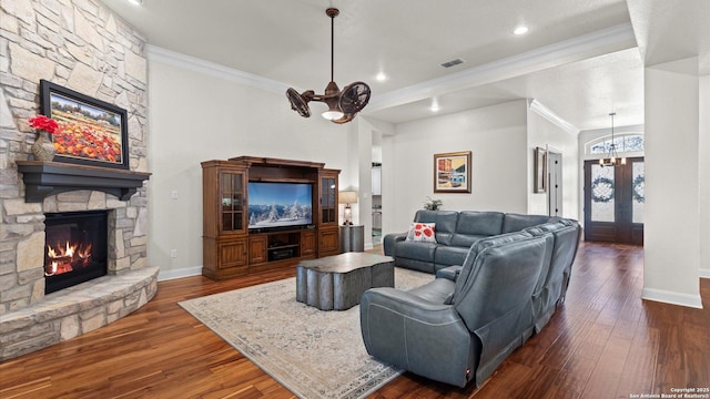 living room with french doors, an inviting chandelier, a stone fireplace, dark hardwood / wood-style floors, and ornamental molding