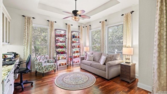 sitting room with a tray ceiling, dark hardwood / wood-style floors, and ceiling fan