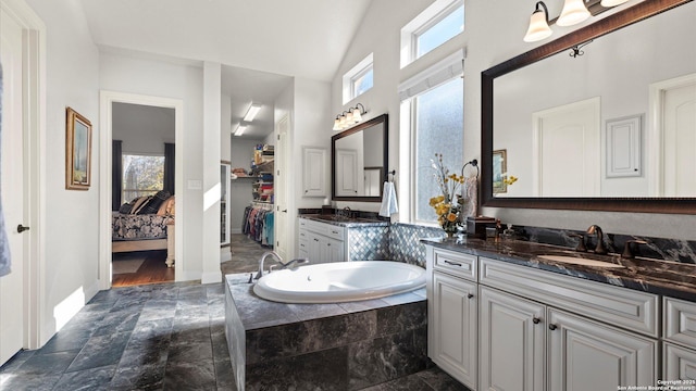 bathroom with vanity, a relaxing tiled tub, and vaulted ceiling