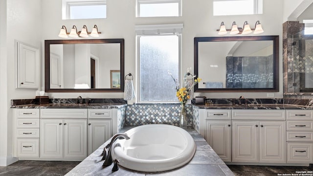 bathroom with vanity and tiled tub