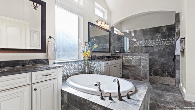 bathroom with shower with separate bathtub, vanity, and vaulted ceiling