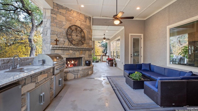 view of patio / terrace featuring ceiling fan, sink, an outdoor kitchen, an outdoor living space with a fireplace, and area for grilling