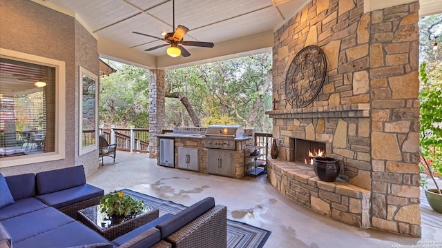 view of patio / terrace with an outdoor living space with a fireplace, ceiling fan, a grill, and an outdoor kitchen