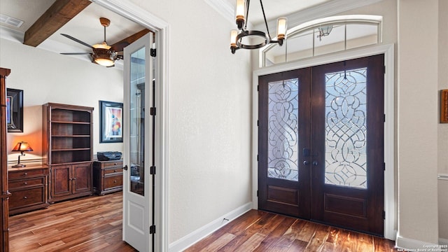 foyer with french doors, ceiling fan with notable chandelier, crown molding, dark wood-type flooring, and beam ceiling