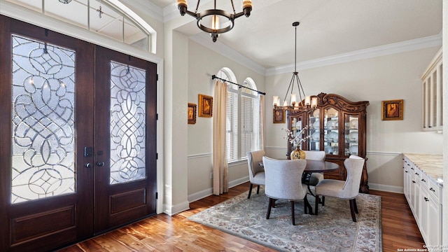 foyer with a chandelier, french doors, crown molding, and wood-type flooring