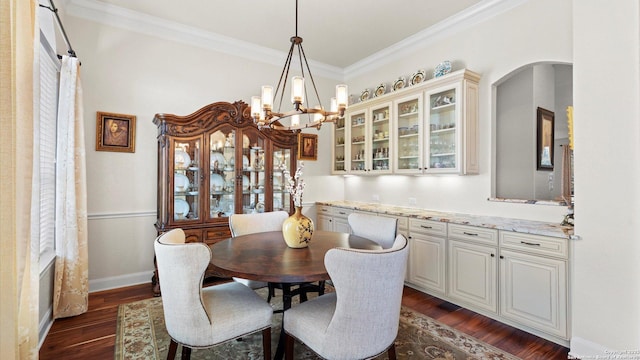 dining space featuring crown molding, dark wood-type flooring, and a notable chandelier