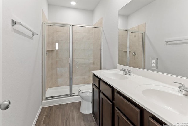 bathroom featuring wood-type flooring, vanity, toilet, and a shower with door